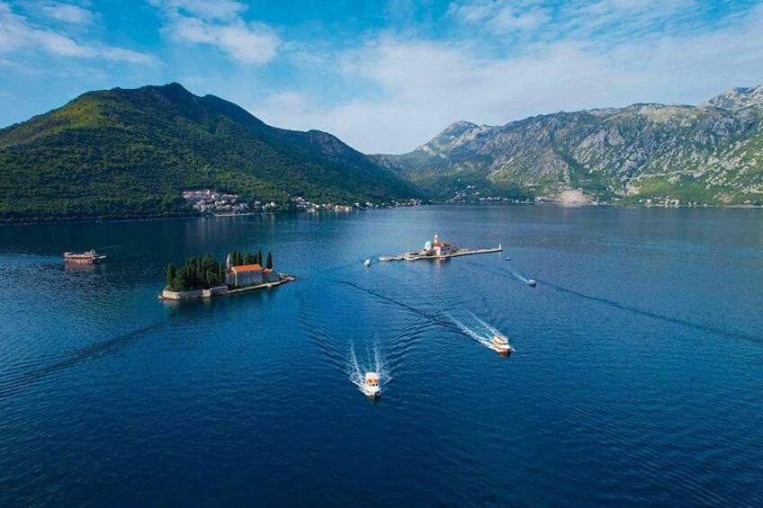 A lake with boats, a small island, and mountains in the background. 2