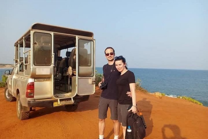 A vehicle parked on a dirt path with a body of water in the background. 3