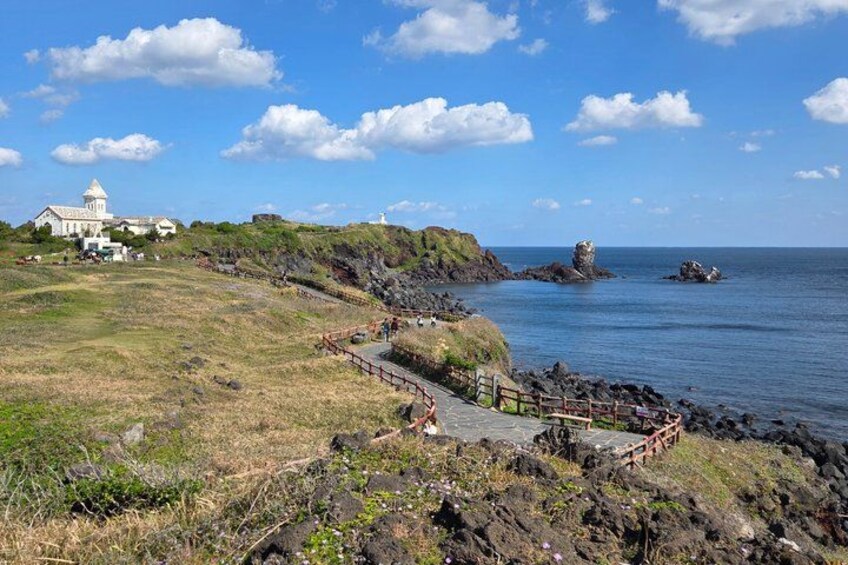 A coastal landscape with a white building, a winding path, and rocky outcrops. 4