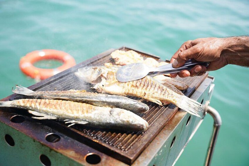 Grillet fisk på en transportabel grill ved vandet. 5