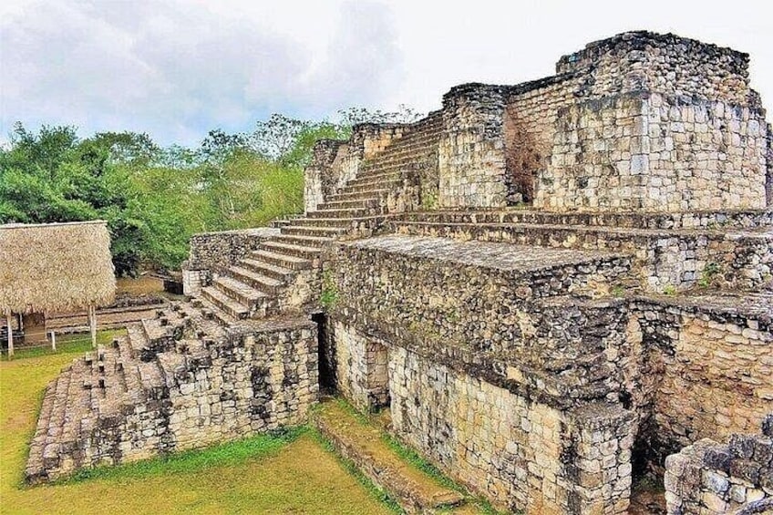 Ancient stone ruins with stepped platforms and a thatched-roof structure. 4