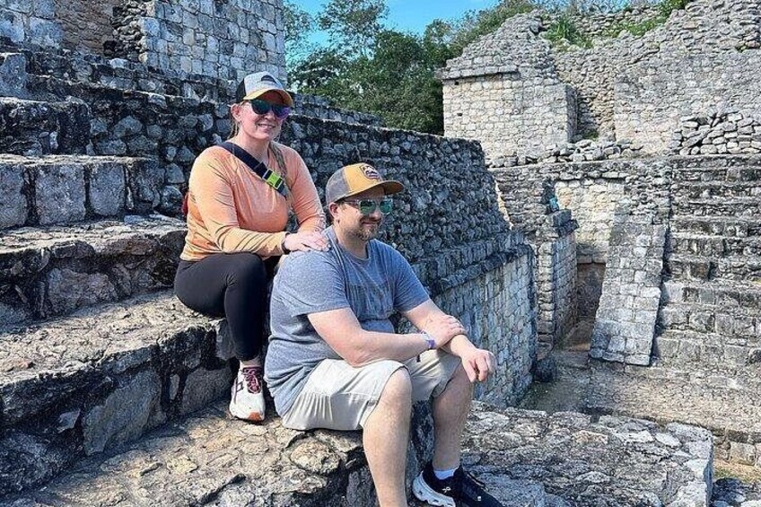 Two people sitting on stone steps at an ancient ruin. 2