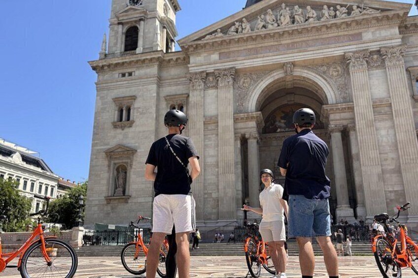 A historic building with a clock tower, people standing in front, and bicycles. 3