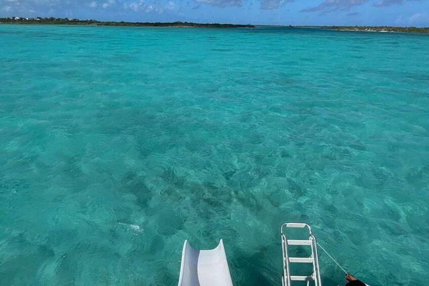 A boat in clear turquoise water with a ladder and a white object in the foreground. 4