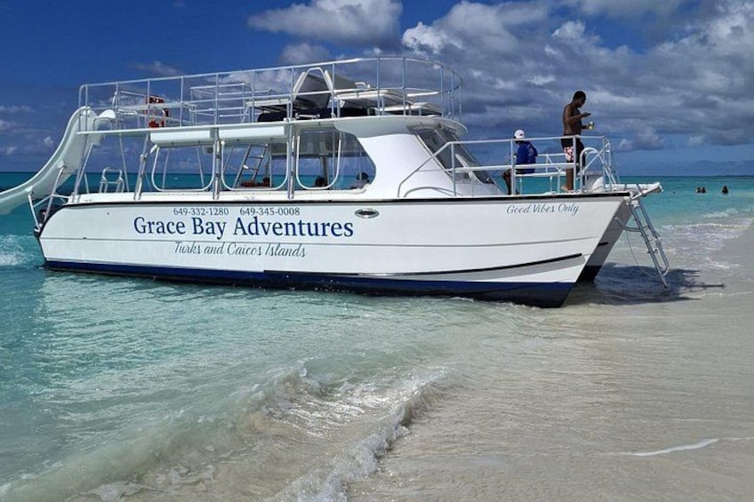 A boat named 'Grace Bay Adventures' on a beach with clear turquoise water. 3