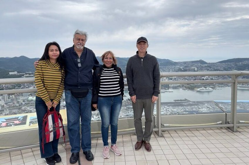 A group of people standing on a balcony with a cityscape and mountains in the background. 3