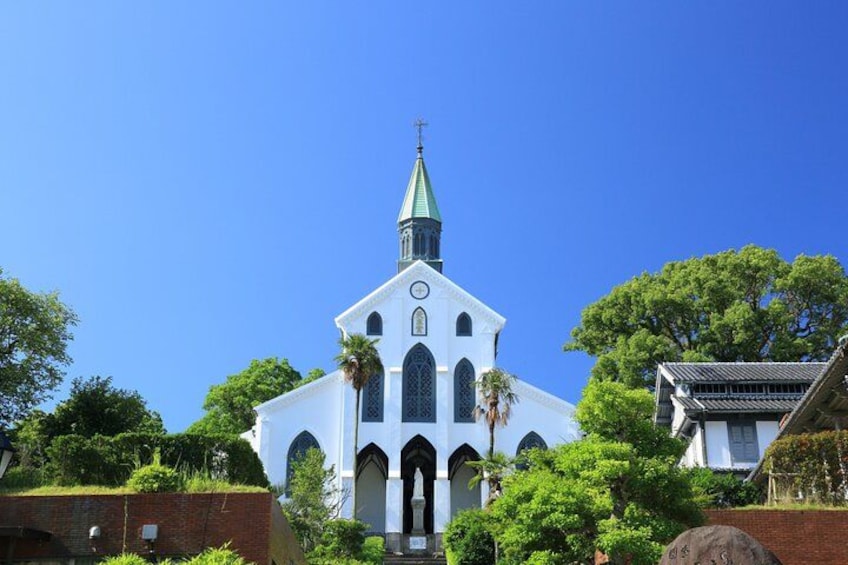 A white church with a green spire, surrounded by trees and a brick wall. 5