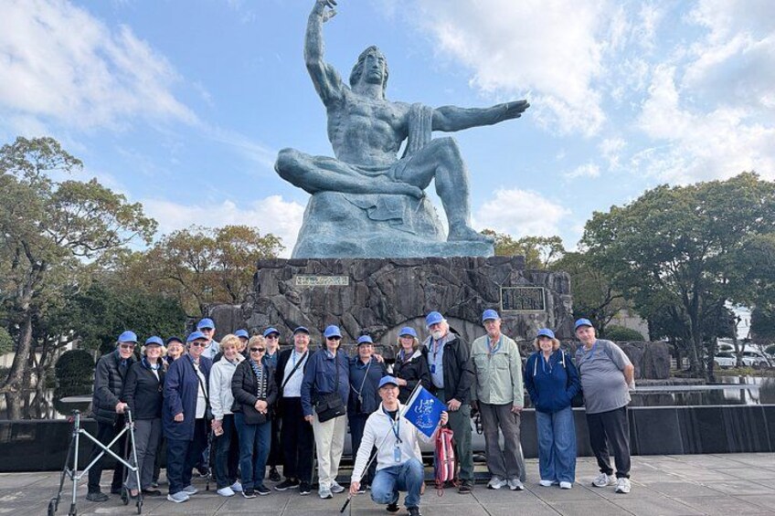 En gruppe mennesker poserer foran en bronzestatue af en siddende kvinde. 2