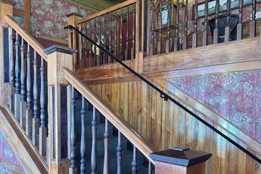 Una escalera de madera con barandillas y pasamanos, que conduce a un piso superior. 3