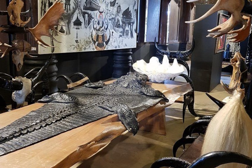Una stanza con diverse teste di animali e una grande scultura finemente decorata su un tavolo di legno. 3