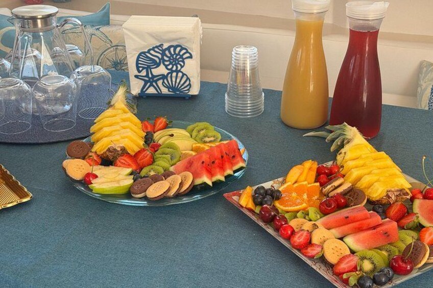 A table with two fruit platters, a pitcher of orange juice, a pitcher of red juice, and a salt shaker. 4