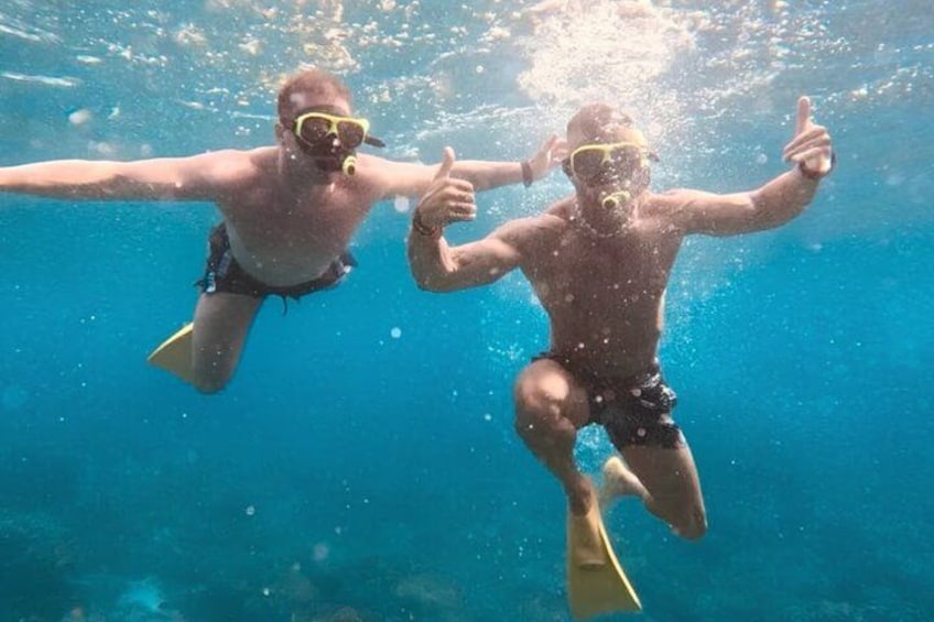 Two people underwater, swimming with fins, giving thumbs up. 3