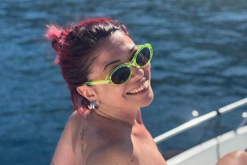 Une personne aux cheveux roux, portant des lunettes de soleil, se tient près d’une étendue d’eau. 2