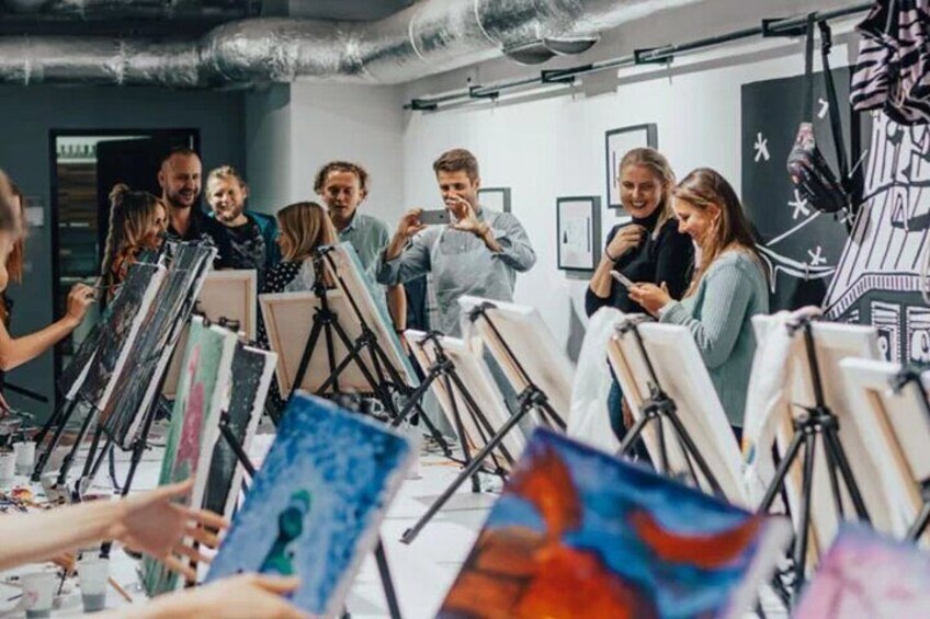 A group of people painting in a studio with easels and canvases. 3