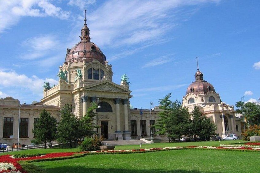 A large building with two domes, surrounded by a well-maintained garden and trees. 3