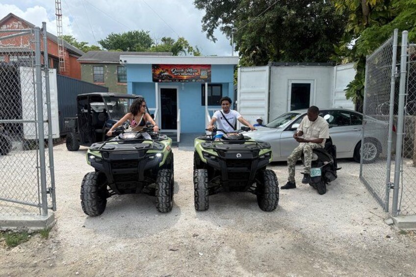 Drei Personen fahren mit Quads in einem eingezäunten Bereich, im Hintergrund sind Gebäude zu sehen. 2