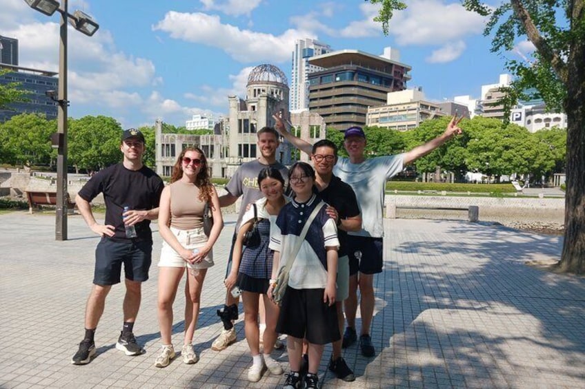 A group of people posing in an urban park with a historic building in the background. 2