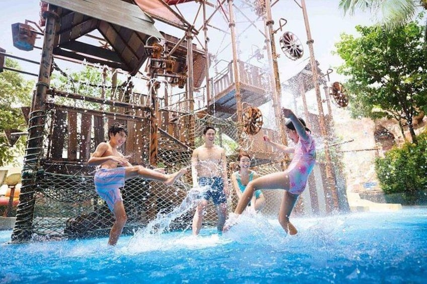 A water park with a pool, wooden structures, and a netted play area. 1