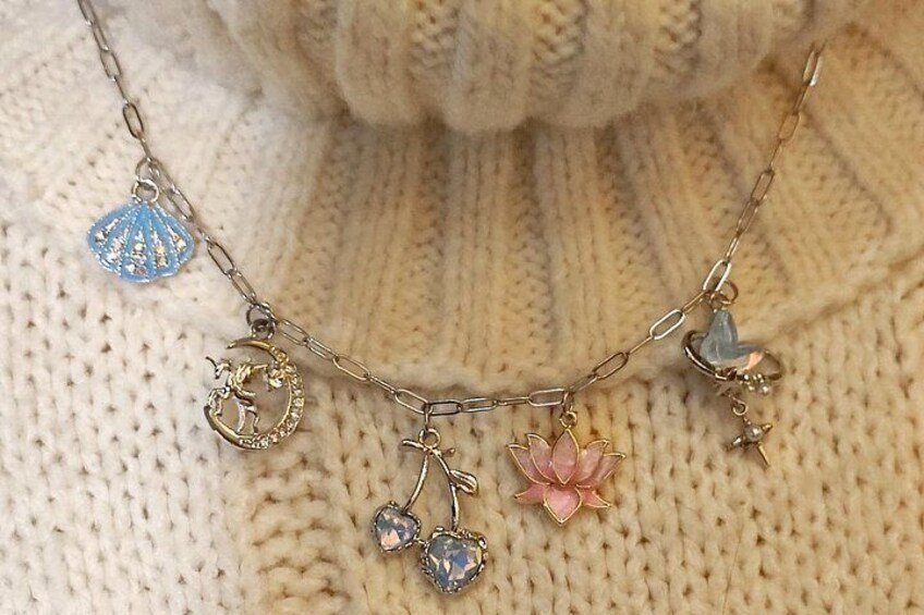 Et smykke med forskellige charms, herunder en blå snegl, en lyserød blomst og en gylden figur. 5