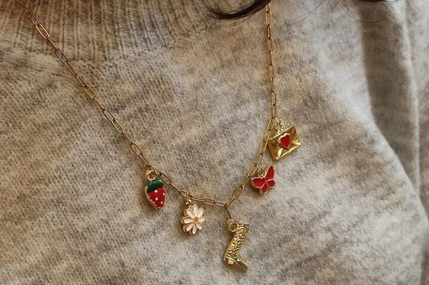 Et smykkehalskæde med charms, blandt andet en jordbær, en blomst og en sommerfugl. 4