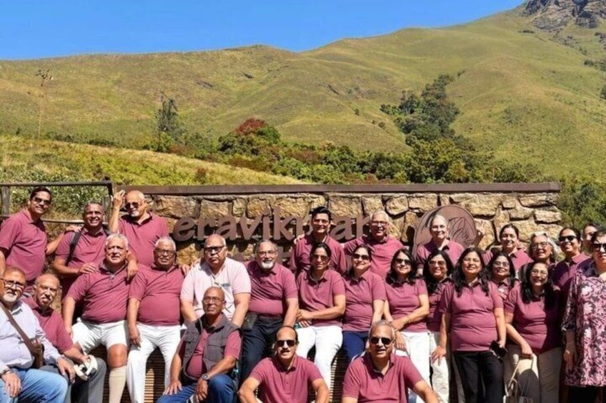 A group of people in a field with a stone wall and hills in the background. 2