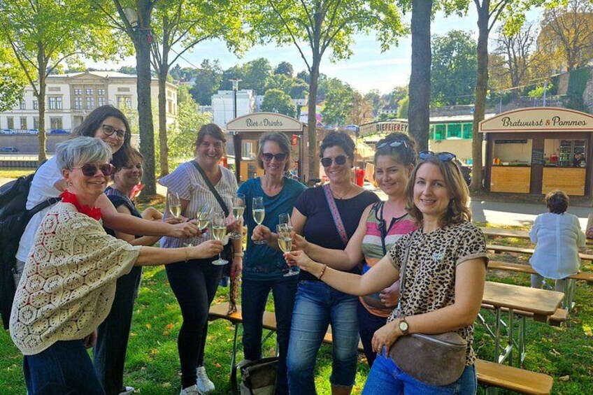 Un groupe de personnes trinquant avec des boissons dans un parc, entouré d’arbres et doté d’espaces de repos en plein air. 2
