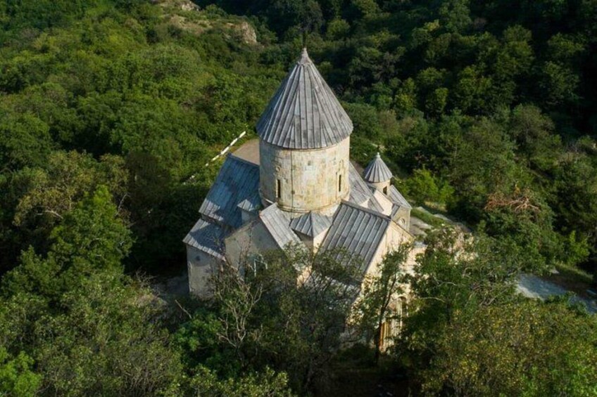 Un'antica chiesa in pietra con tetto a cono, circondata da una fitta foresta. 2