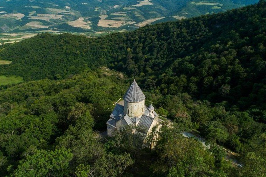 Un edificio storico in pietra con un tetto conico, circondato da una fitta foresta. 3