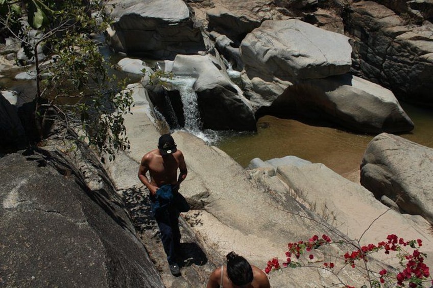 A waterfall, large rocks, and a person standing on a rock. 5