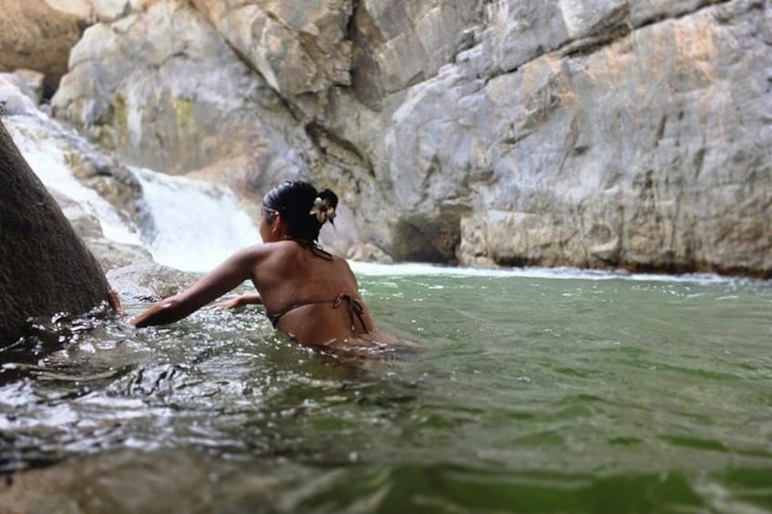 A person in a natural water body with rocky surroundings. 1