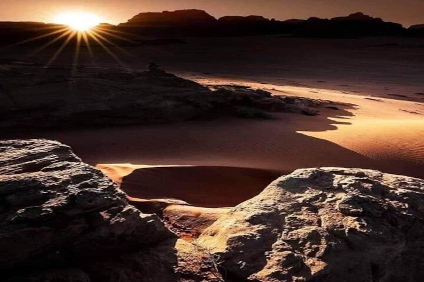 Paisaje desértico con una formación rocosa iluminada por el sol y un pequeño charco de agua. 2