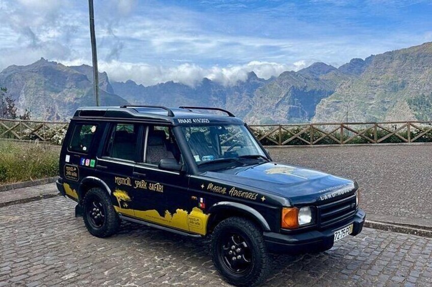 Un SUV negro con gráficos amarillos estacionado en un camino adoquinado con montañas al fondo. 5