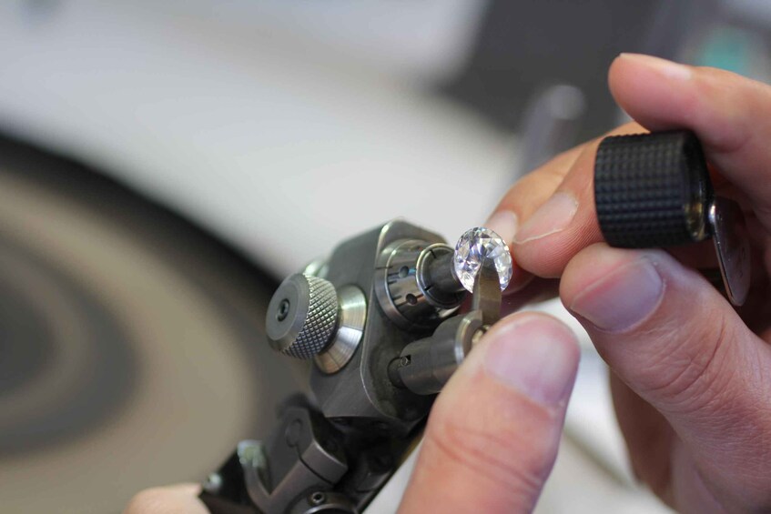 A person holding a diamond with a ring on a tool. 2