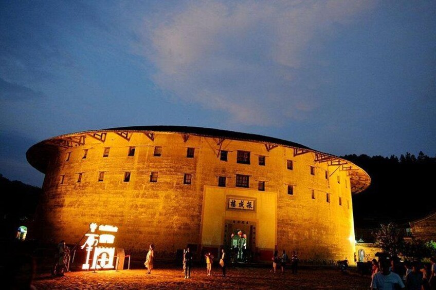 Un edificio circular grande e iluminado con una entrada central y varias ventanas. 1