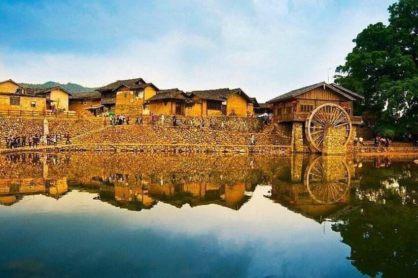 Edificios tradicionales, una noria grande y una superficie acuática tranquila y reflectante. 5