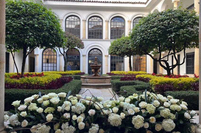 Un cortile con una fontana, circondato da siepi curate e piante fiorite. 4