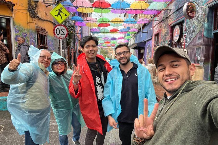 Un gruppo di persone cammina per strada sotto ombrelli colorati. 1