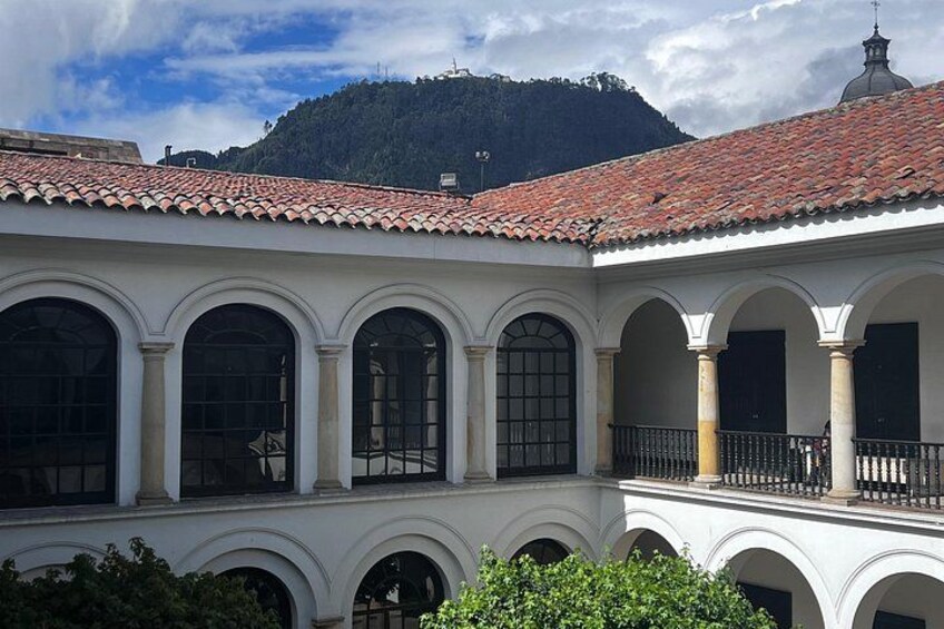 Un cortile con archi, un tetto in tegole e una montagna sullo sfondo. 5