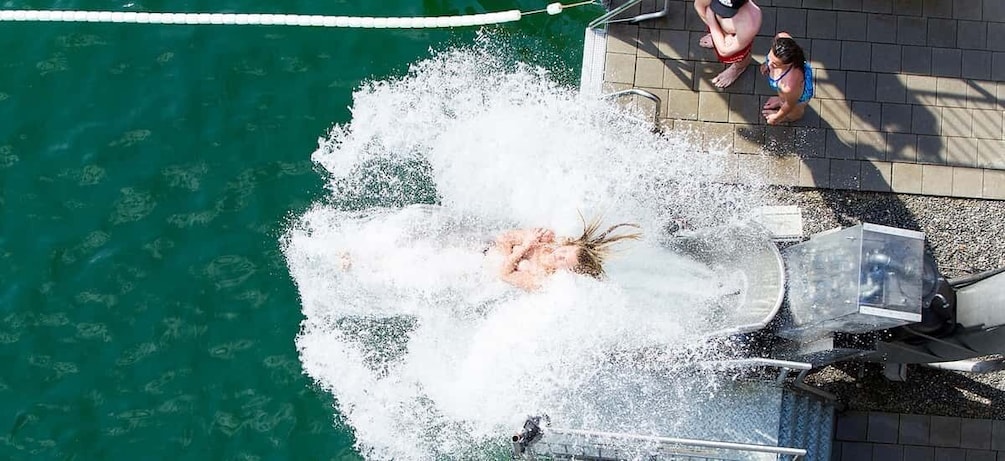 A person submerged in water with a splash, a pool edge, and a tiled walkway. 5