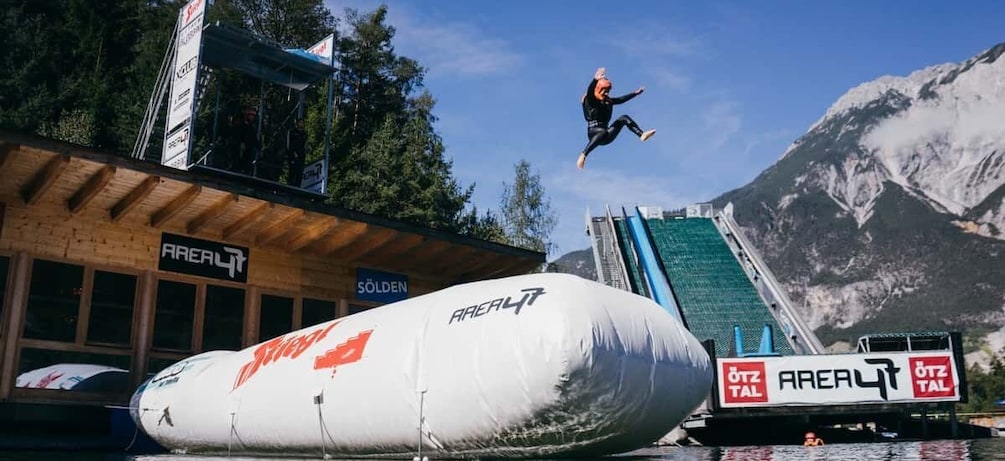 A person jumping off a ramp, a large inflatable, and a mountain in the background. 2