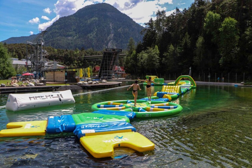 A swimming pool with inflatable water slides and a mountain in the background. 3