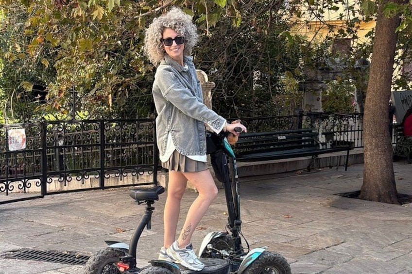 Eine Person fährt auf einem Segway auf einem gepflasterten Weg, im Hintergrund Bäume und ein Zaun. 4
