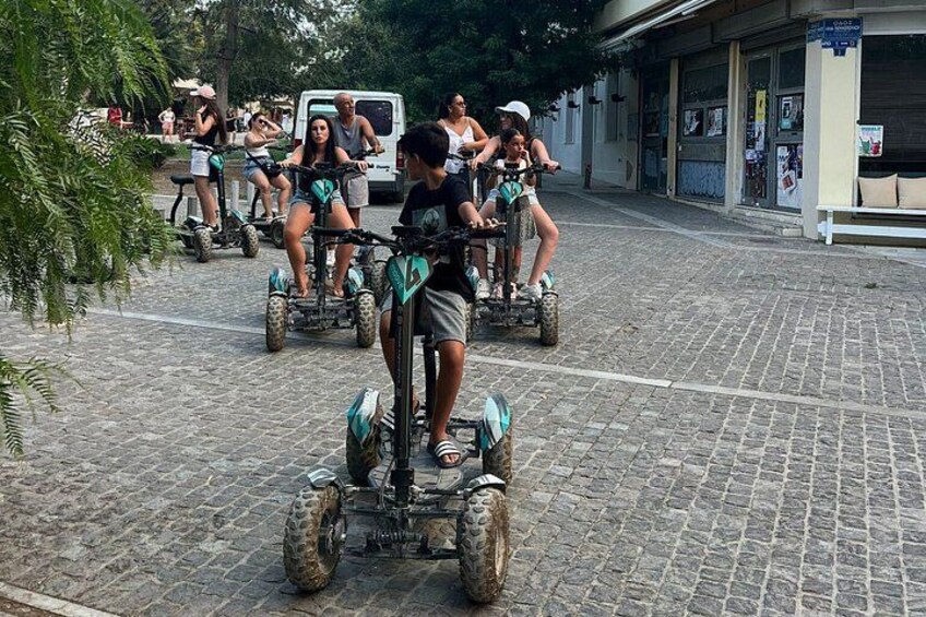 Menschen fahren mit Segway-ähnlichen Fortbewegungsmitteln über eine Kopfsteinpflasterstraße. 5