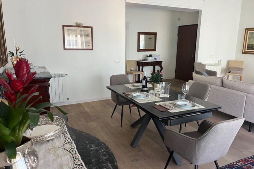 Een eethoek met een tafel gedekt voor twee personen, een bank en een decoratieve plant. 3