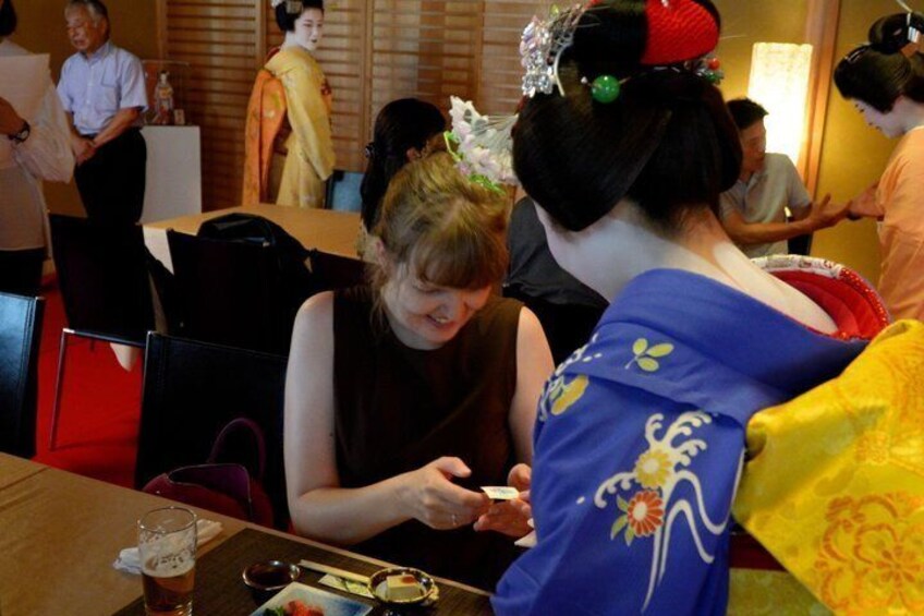Two individuals seated at a table, one in a black dress and the other in a blue kimono with floral patterns. 5