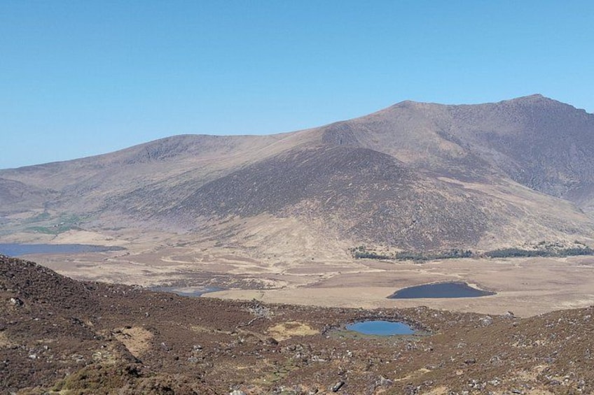 A mountainous landscape with a clear sky, a small lake, and rocky terrain. 4