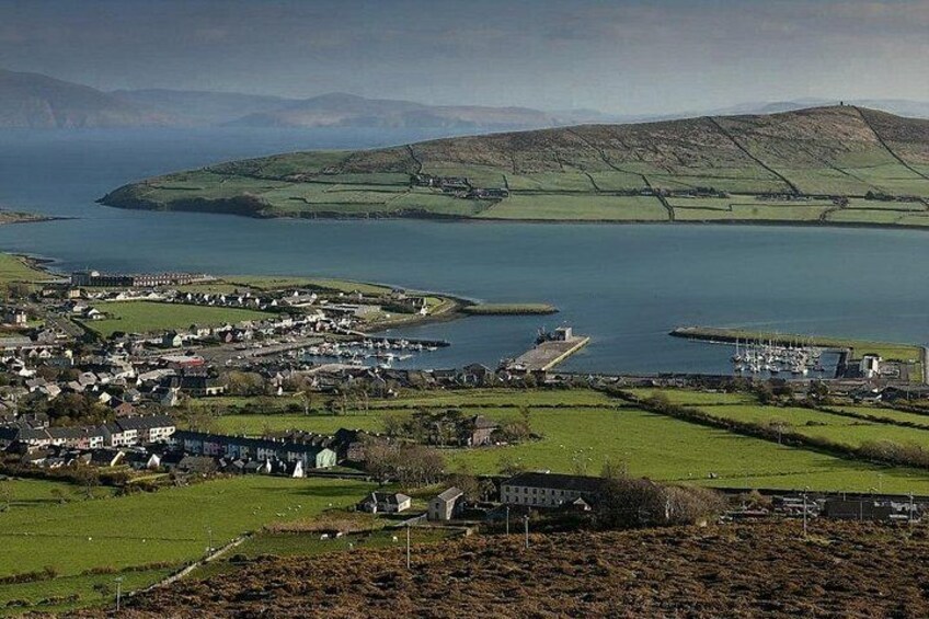 A coastal town with houses, a marina, and a hilly landscape in the background. 2