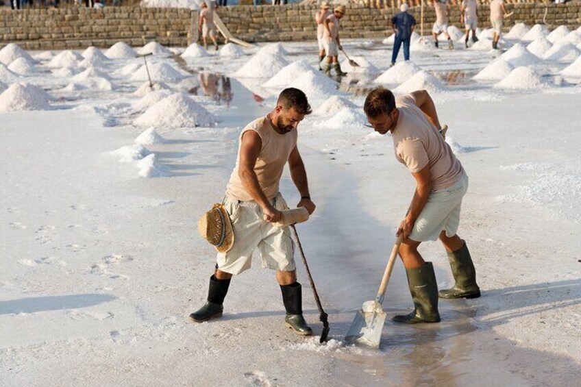 Two men shoveling salt into piles on a beach. 3