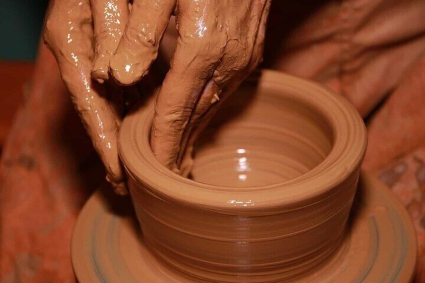 Hands shaping a clay pot on a spinning wheel. 4