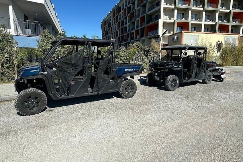 Två terrängfordon står parkerade på en gata med byggnader i bakgrunden. 2